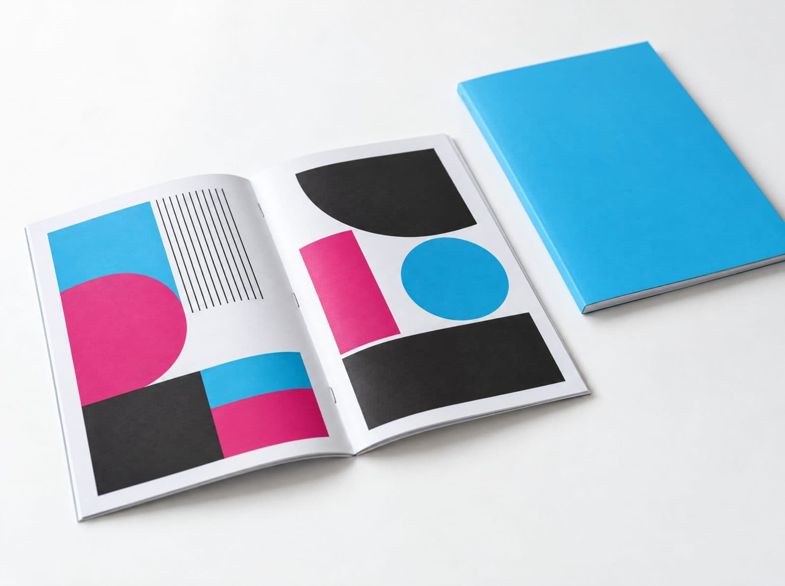 A saddle stitched booklet lying open next to a perfect bound catalog