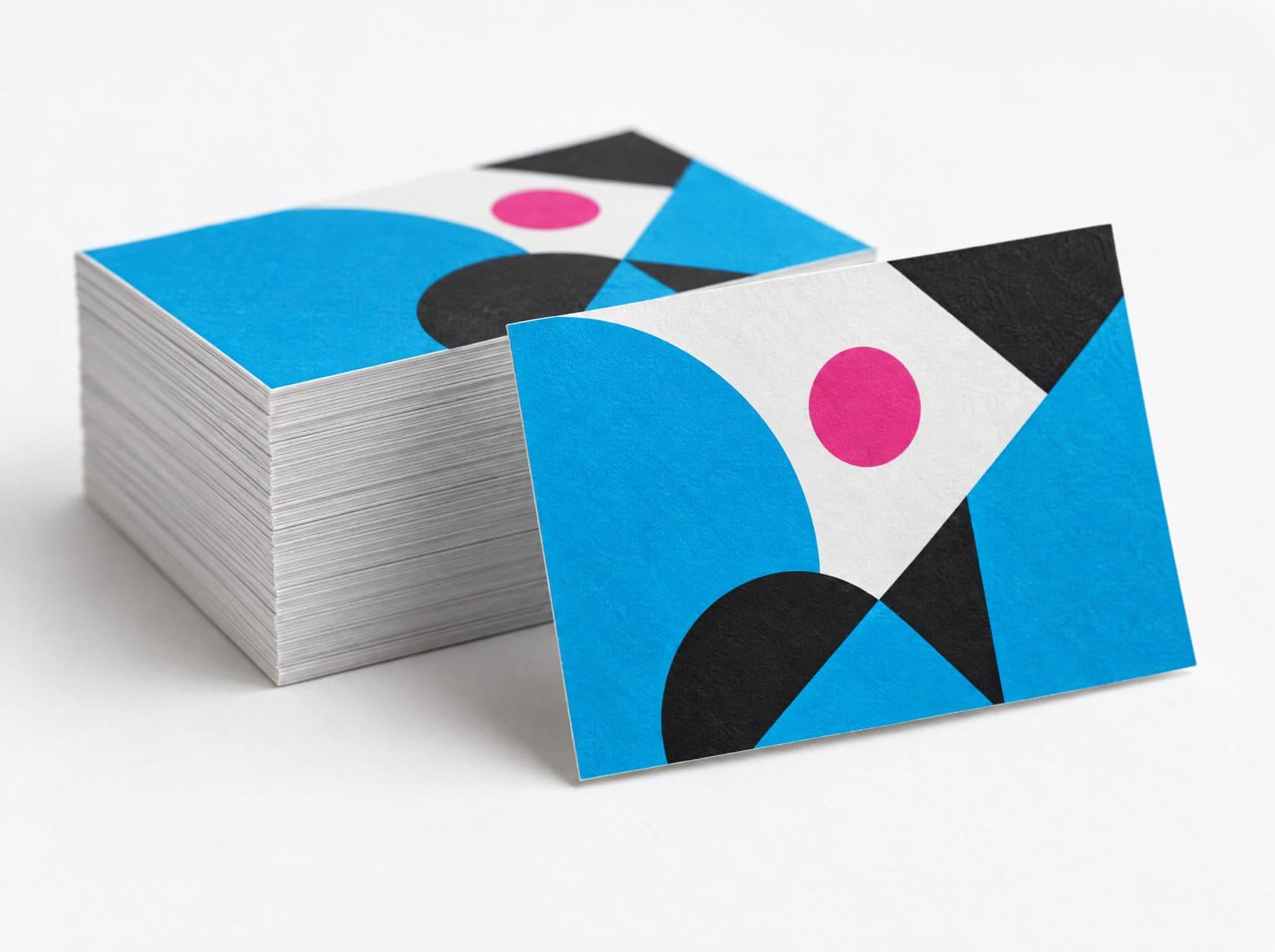 A stack of thick matte business cards printed in cyan, magenta and black